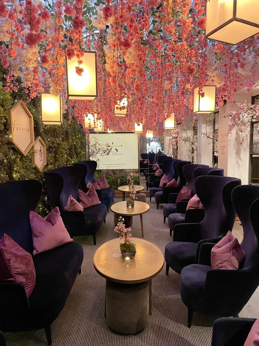 A ceiling of hanging blossom above velvet chairs