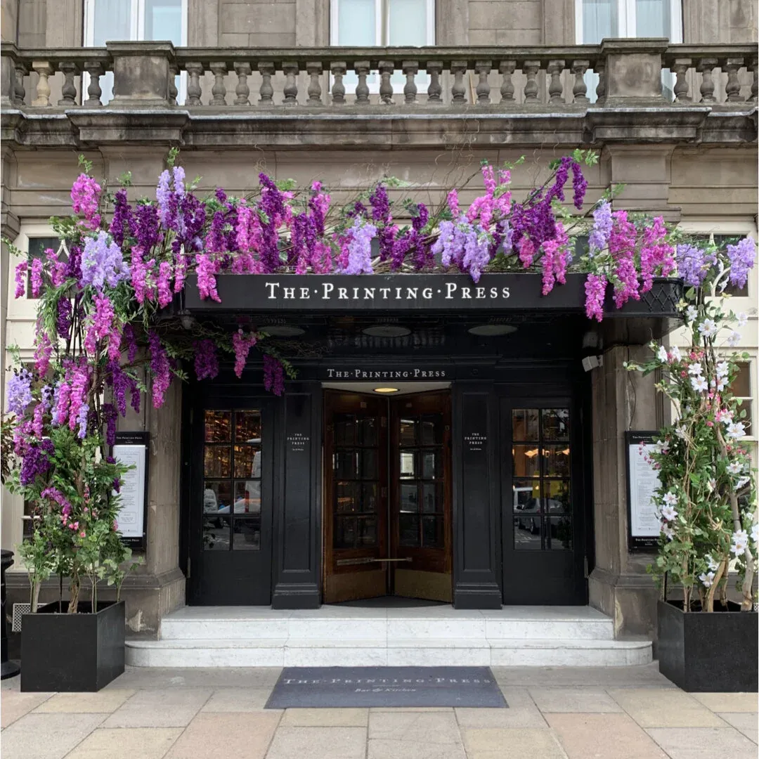 Purple wisteria cascading over the entrance to The Printing Press