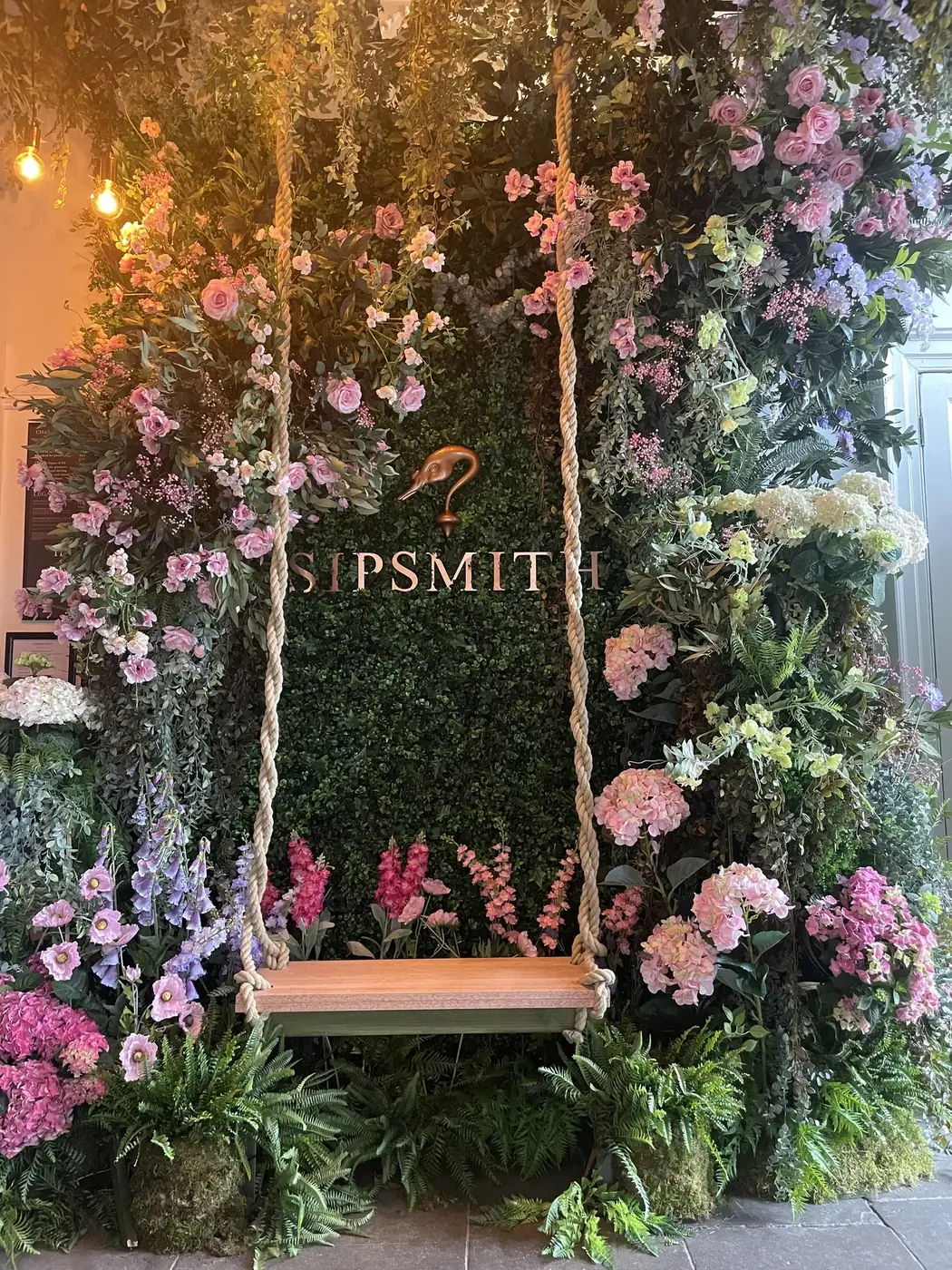 A flower wall with a rope swing for Sipsmith