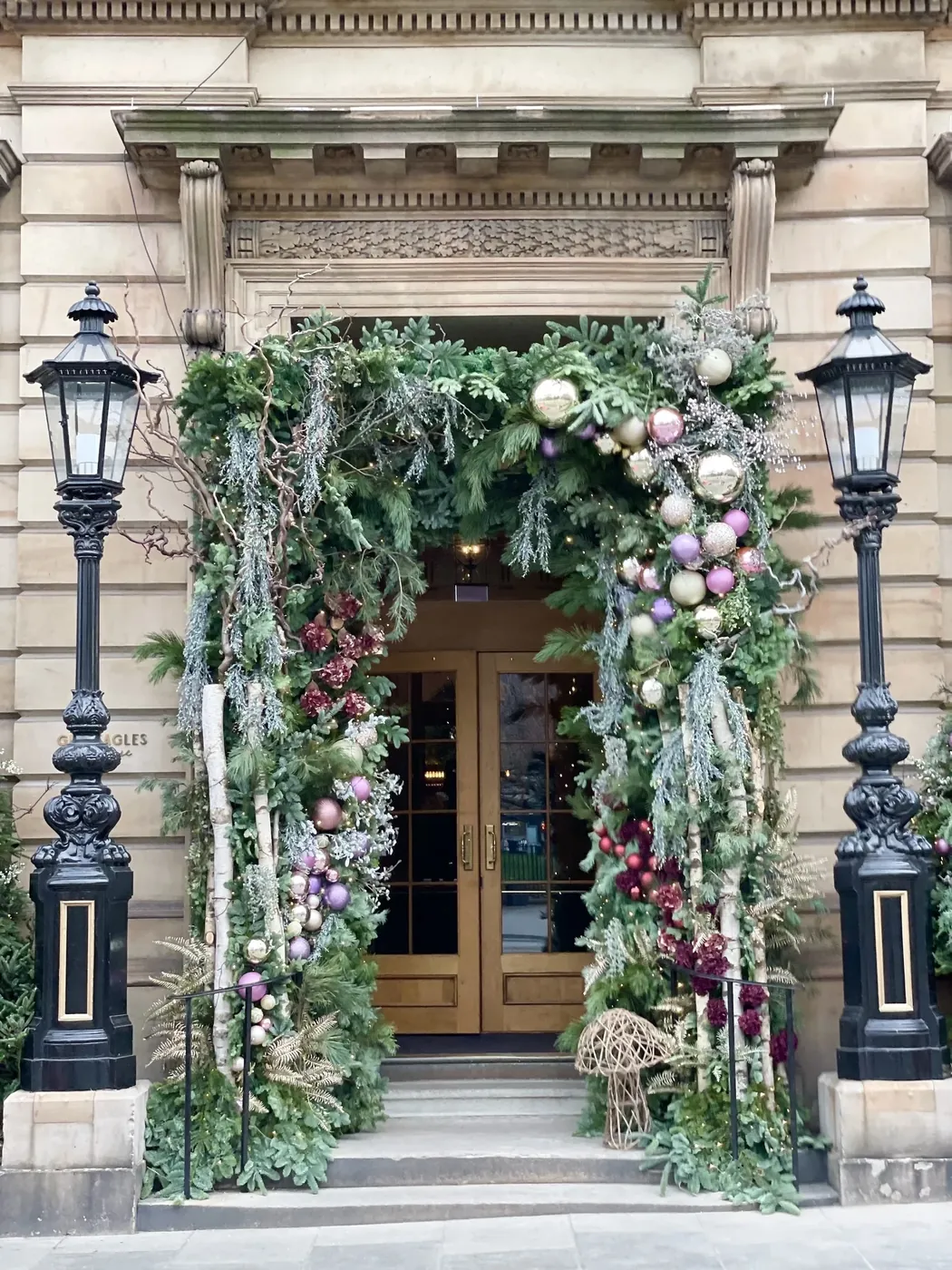 A doorway between two lamps dressed in garland and baubles