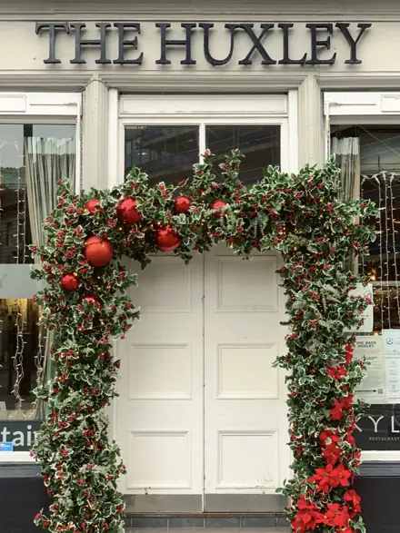 Holly and red berry garland around the doors of The Huxley