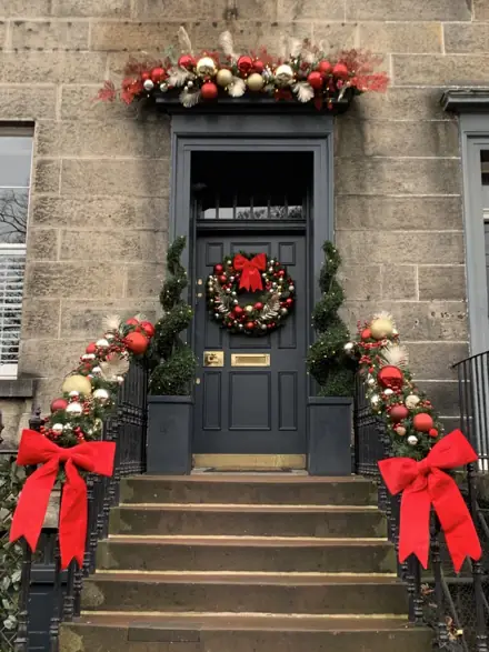 Garlands with red bows running up the steps of a townhouse